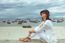 Frau mit Hut und Sonnenbrille sitzt an der Wand am Strand, my khe, danang city, vietnam — Stockfoto
