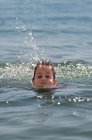 Primer plano de niño feliz nadando en el mar - foto de stock