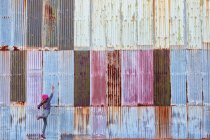 Девушка прыгает перед красочной гофрированной металлической стеной — стоковое фото