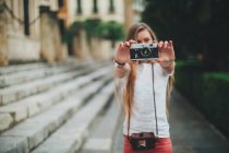 Young woman holding retro film camera next to stairs — Stock Photo