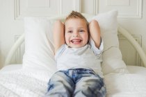 Carino bambino sorridente e sdraiato sul letto — Foto stock