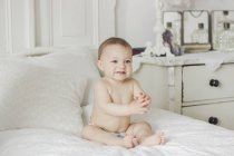 Ritratto di bambino sorridente seduto sul letto in camera da letto — Foto stock