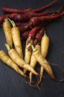 Vista ravvicinata delle carote cimeli gialle e viola su sfondo nero — Foto stock