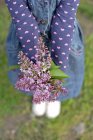 Primer plano de Chica sosteniendo ramo de flores de color lila - foto de stock