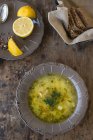 Folk kitchen representation, chicken soup with rye bread and lemon, top view — Stock Photo
