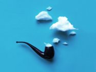 Fumée conceptuelle sortant d'un tuyau sur fond bleu — Photo de stock