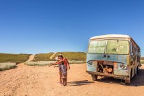 Drei Kinder in Wüste neben beschädigtem Bus — Stockfoto