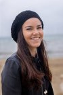 Портрет улыбающейся женщины в черной шляпе на пляже — стоковое фото