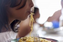 Retrato de cerca de una chica comiendo espaguetis - foto de stock