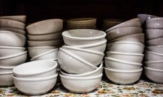 Stacks of white shiny empty bowls on shelf, close-up — Stock Photo