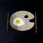 Conceptual plate and fried egg, black background — Stock Photo