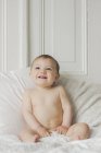 Ritratto di bambino sorridente seduto sul letto in camera da letto — Foto stock