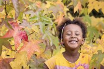 Portrait of smiling girl in colorful tree in autumn — Stock Photo