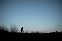 Scenic view of silhouette of woman walking at dusk — Stock Photo
