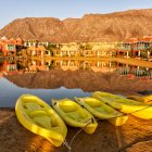 Scenic view of yellow boats on beach, houses in background — Stock Photo