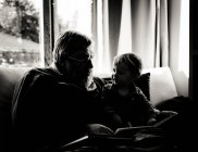 Silueta del abuelo leyendo a su nieto en casa - foto de stock