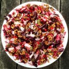 Insalata di noci, ravanello e ribes rosso sul piatto bianco sul tavolo di legno — Foto stock