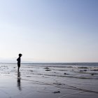 Bambino in piedi sulla spiaggia e guardando il mare — Foto stock