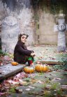 Menino vestindo trajes de Halloween sentado no cemitério — Fotografia de Stock