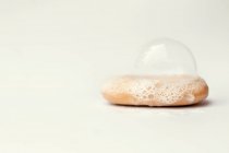 Bubbles on bar of soap against white background — Stock Photo