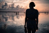Indonésia, Bali, Legian, Silhueta de mulher de pé na praia ao pôr do sol — Fotografia de Stock