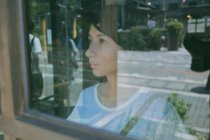 Close-up view of beautiful woman looking through window — Stock Photo
