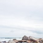 Живописный вид на скалы на пляже под белым небом — стоковое фото