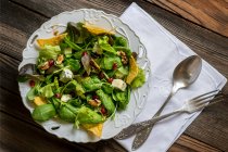 Green salad with tortilla chips lying over wooden background — Stock Photo