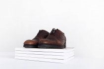 Par de zapatos en una pila de revistas, fondo blanco - foto de stock