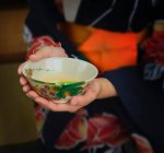 Imagen recortada de niña sosteniendo taza de té verde - foto de stock