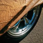 Close-up high angle view of Rim and car cover on asphalt road — Stock Photo