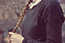Обрезанное изображение школьницы, держащей волосы в руках — стоковое фото