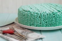 Cake covered in green buttercream icing on platter — Stock Photo