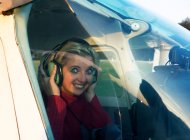 Mujer sonriente sentada en un avión pequeño - foto de stock