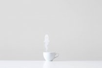 Conceptual cup with ghost steam against grey wall — Stock Photo