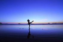 Side view of silhouette of boy kicking on beach — Stock Photo