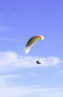 Person paragliding in front of blue sky with clouds — Stock Photo
