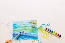 Overhead view of a boy painting with watercolors — Stock Photo