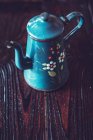 Повышенный вид чайника с цветочным узором на деревянном столе — стоковое фото