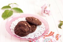 Три шоколадных печенья на розовой тарелке — стоковое фото