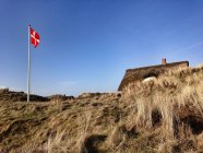 Casa de verão dinamarquesa e bandeira acenando na Dinamarca — Fotografia de Stock