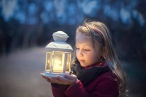 Fille réfléchie tenant une lanterne la nuit — Photo de stock