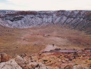 Vista panorámica del hombre caminando en el cráter de meteoros - foto de stock