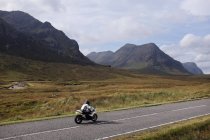 Man riding motorbike on road in mountains, Highlands, Escócia, EUA — Fotografia de Stock