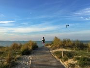 Visão traseira de uma mulher em pé na praia assistindo kiteboarder, La Rochelle, França — Fotografia de Stock