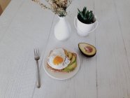 Авокадо і смажене яйце на тості сніданок на дерев'яному столі — стокове фото
