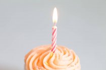 Cupcake mit brennender Kerze auf weißem Hintergrund — Stockfoto