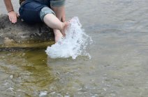 Imagem cortada de mulher espirrando pés no mar — Fotografia de Stock