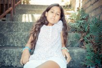 Retrato de menina sentado em escadas ao ar livre e olhando para a câmera — Fotografia de Stock