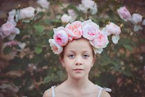 Menina usando uma cobertura para a cabeça com rosas olhando para a câmera — Fotografia de Stock